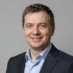 Портрет уверенного российского бизнесмена с дружелюбным взглядом на размытом нейтральном фоне в студии