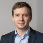 Портрет уверенного российского бизнесмена с дружелюбным взглядом на размытом нейтральном фоне в студии